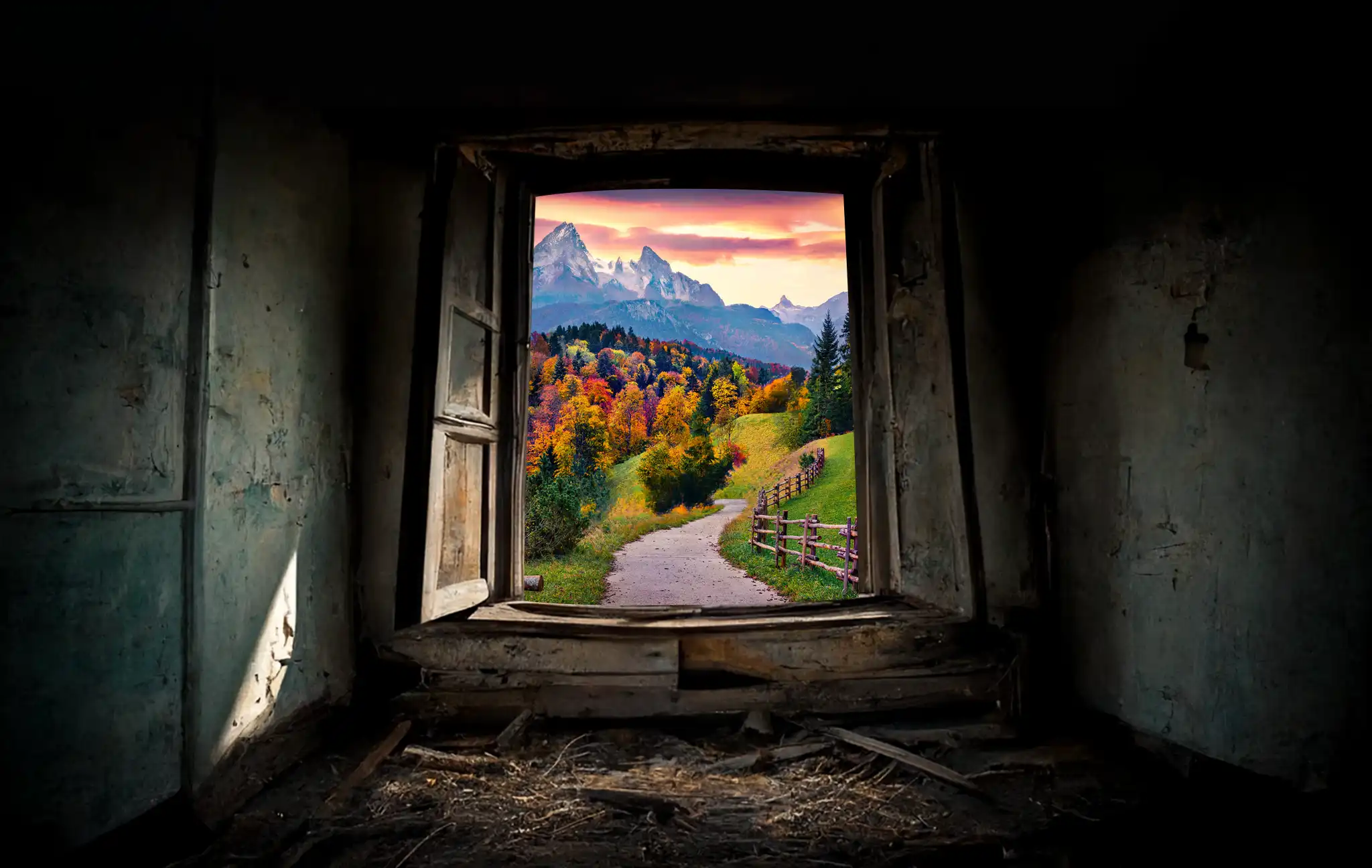 Large window looking out at a winding path heading towards mountains.